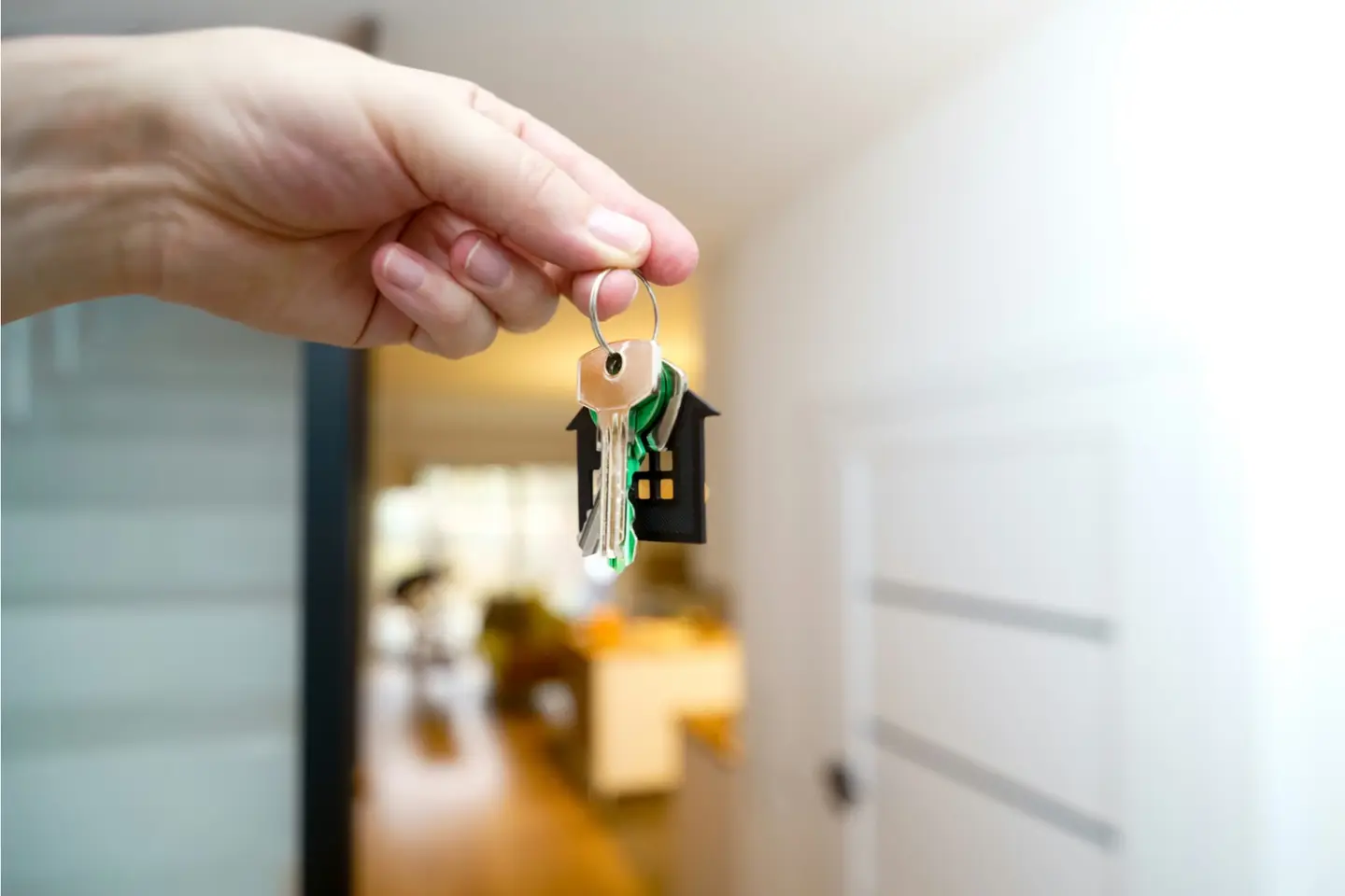 A hand holding a set of house keys in an open doorway