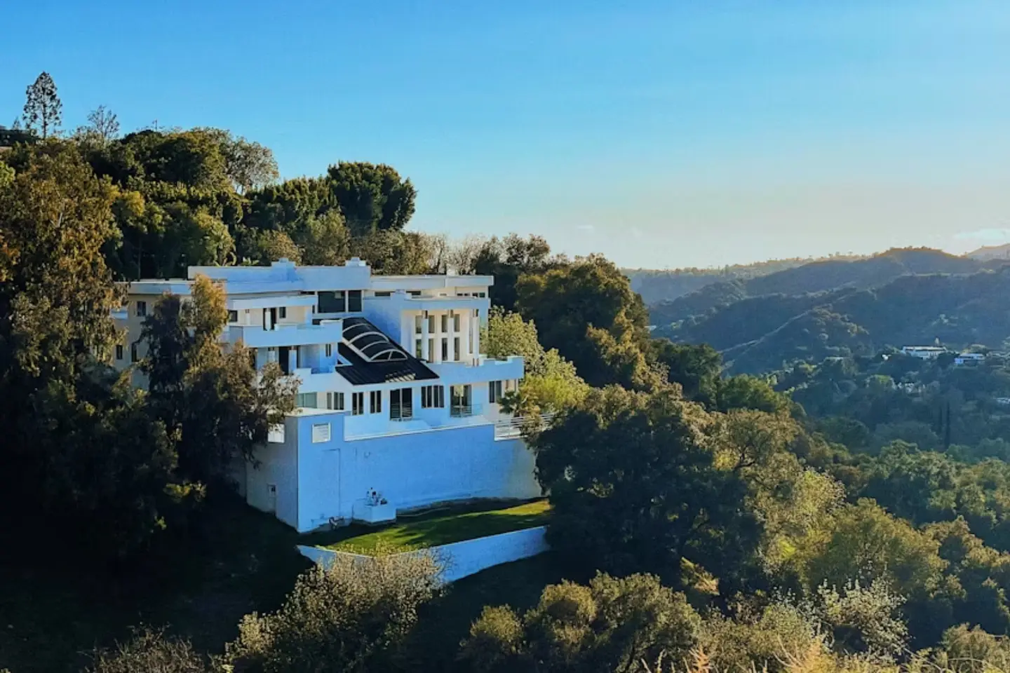 A white hillside home above a wooded valley (illustrative foothill-style image, not this canyon)