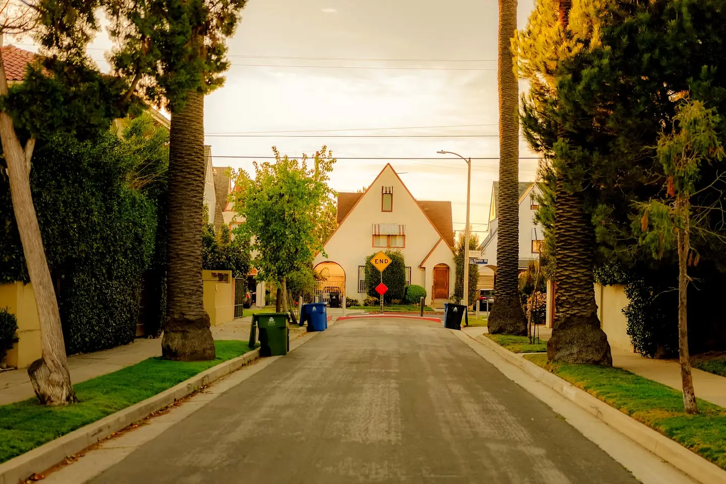 A palm-lined residential street of bungalows at dusk (illustrative Southern California street, not this community)